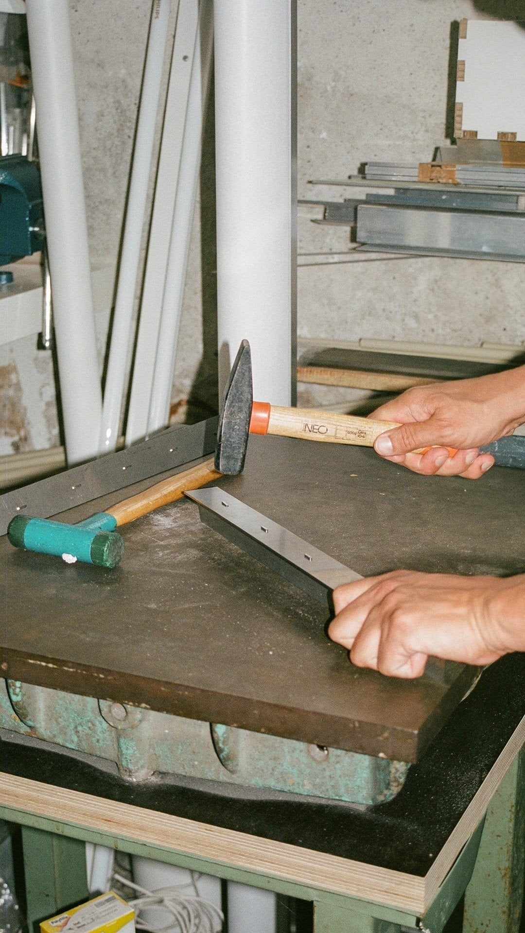 Hands join two aluminium parts with hammer and punch, the hand-riveting technique behind the Rivet Series.
