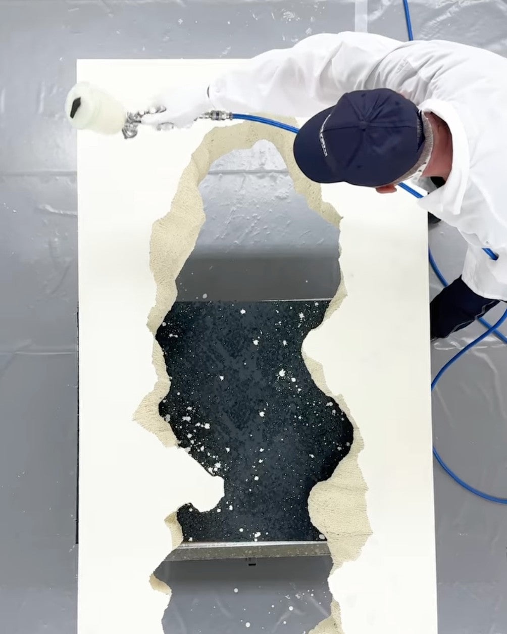 Seen from above, a Gufram craftsman sprays a finish onto a piece in the workshop