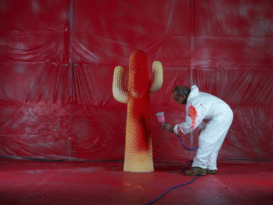 A painter in protective overalls spray-coats a Cactus coat rack red in Gufram's paint booth.