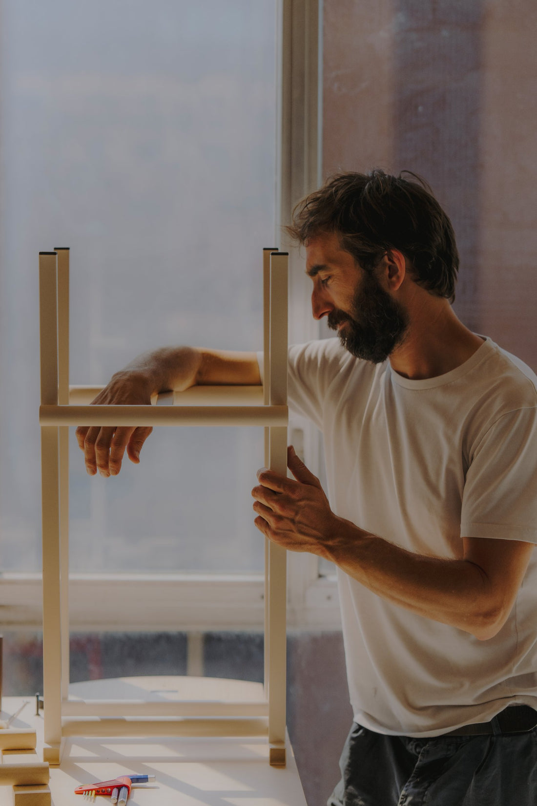 A designer assembles a prototype of the Taburete 8 bar stool for HAY in soft daylight