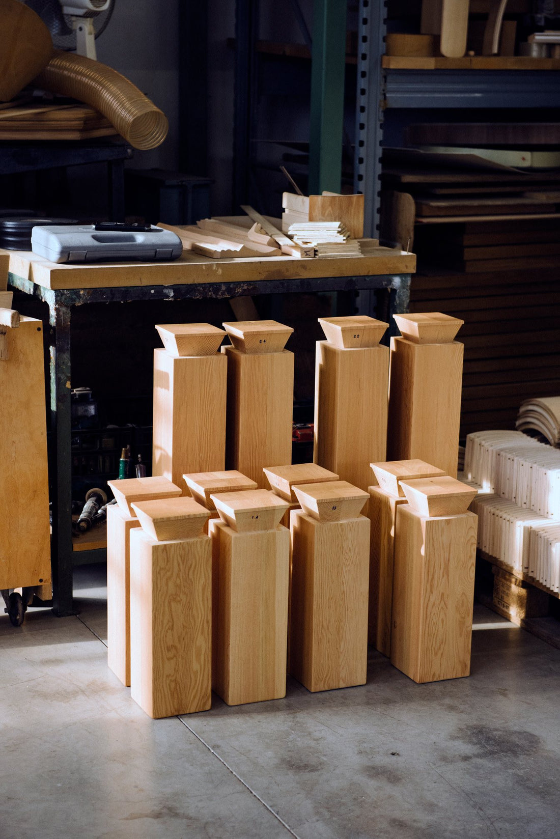 Freshly made solid wood legs with dovetail tenons for the Max Table, stacked in front of the workbench.