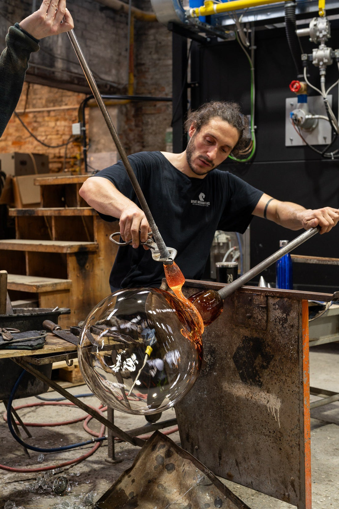 A glassmaker in Murano shaping a mouth-blown glass object on the blowpipe.