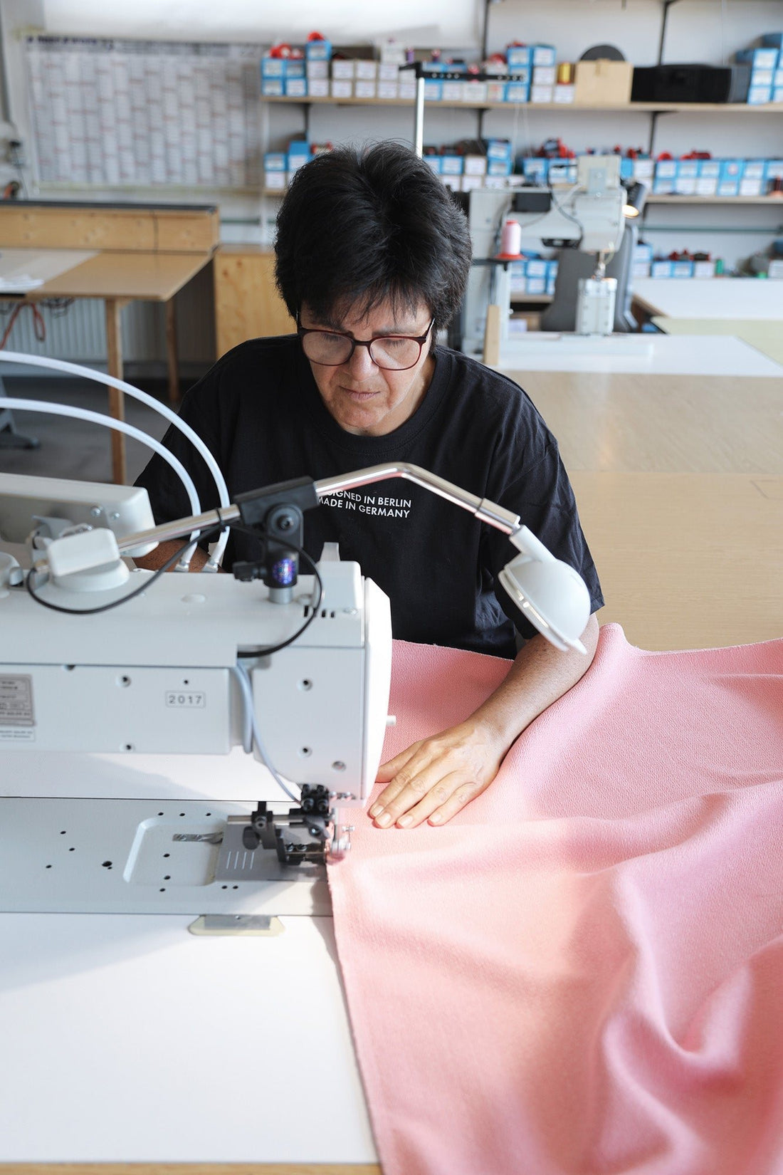 A seamstress at an industrial sewing machine sews pink upholstery fabric for an OUT sofa.