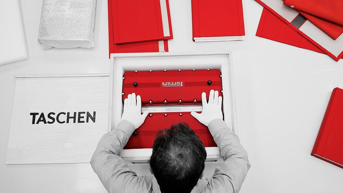 A bookbinder in white gloves places the Ferrari limited edition into its wooden box, linen-bound books around.