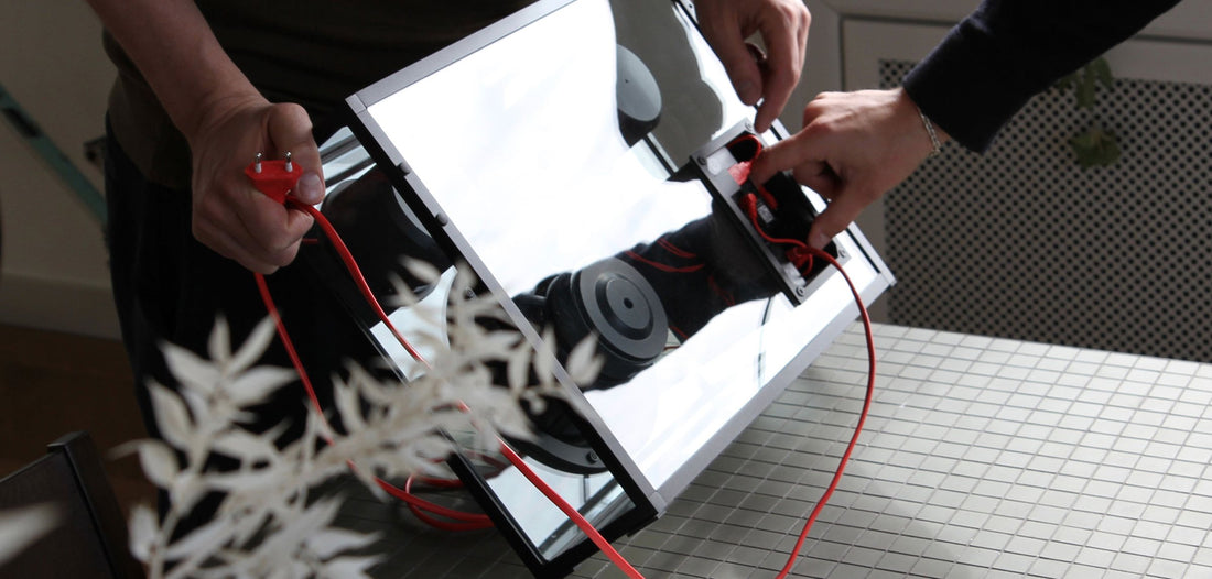 Two pairs of hands fit the electronics module with its cable into an opened Transparent Speaker.