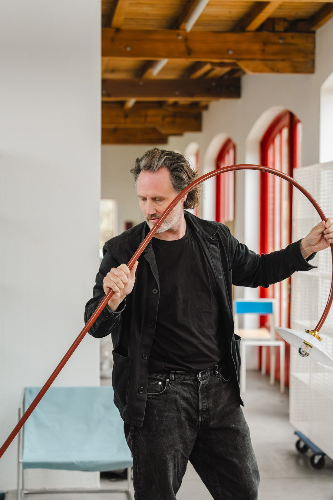 Hannes Van Severen holds the long curved steel arm of a lamp in the Muller Van Severen studio.